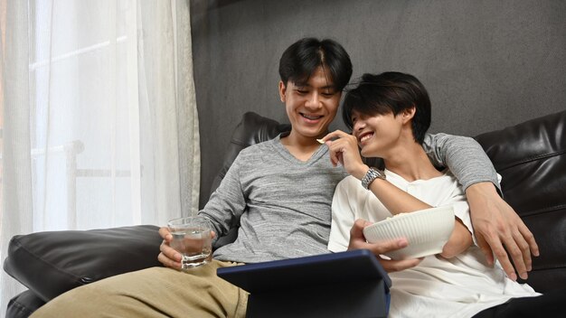 Amando o casal masculino do mesmo sexo usando tablet digital juntos no sofá Relacionamentos homossexuais e conceito de estilo de vida de amor alternativo