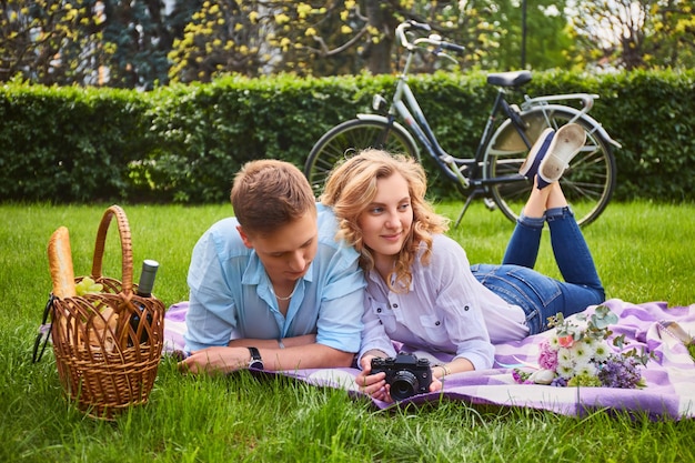 Amando o jovem casal tirando fotos e relaxando em um piquenique em um parque.