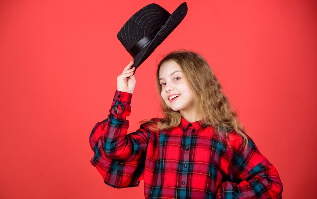 Amando su nuevo estilo Modelo de moda inclinando su sombrero para saludar Niña pequeña con cara linda y cabello largo Niña pequeña con estilo casual Moda y estilo para niños