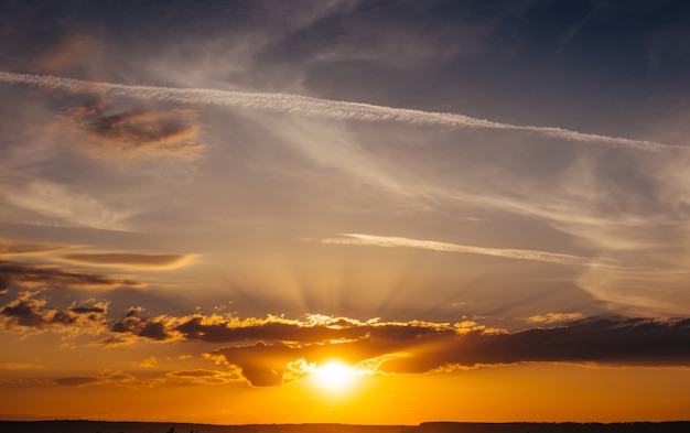 Amanecer al atardecer con nubes, rayos de luz y otros elementos atmosféricos.