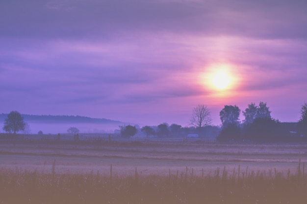 Amanecer en el campo temprano en la mañana brumosa. Paisaje rural