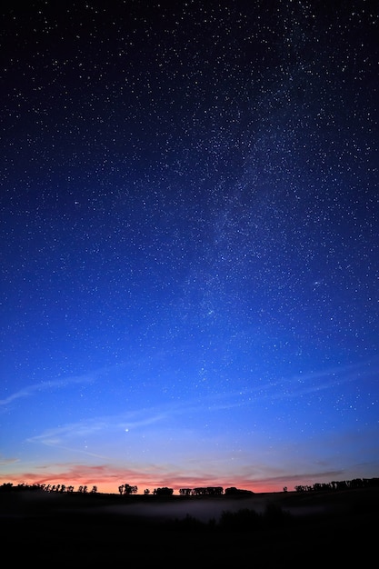 Amanecer en un cielo de fondo estrellado y la Vía Láctea.