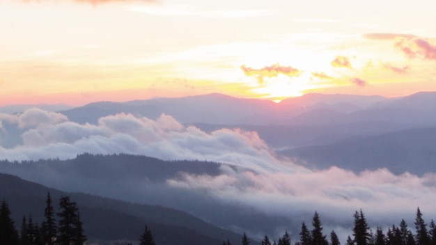 Amanecer colorido romántico en las montañas El sol sube las nubes azules y naranjas fluyen en el cielo Majestuoso paisaje maravilloso Timelaps en cámara lenta Imágenes de 4K