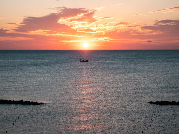 Amanecer en el horizonte con barco de pescadores