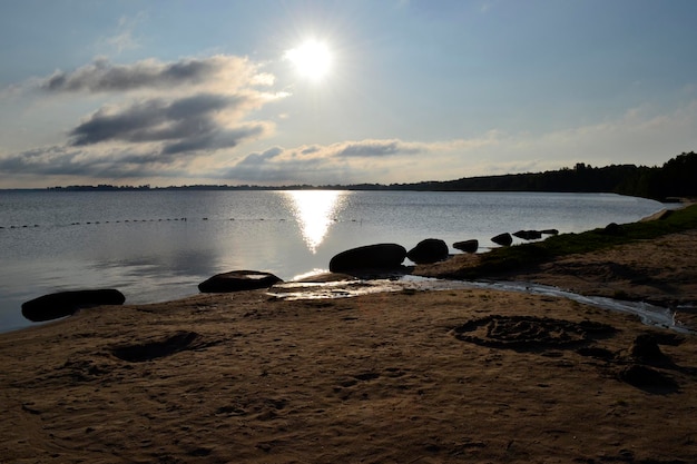 Amanecer en el lago con orilla de arena y piedras.