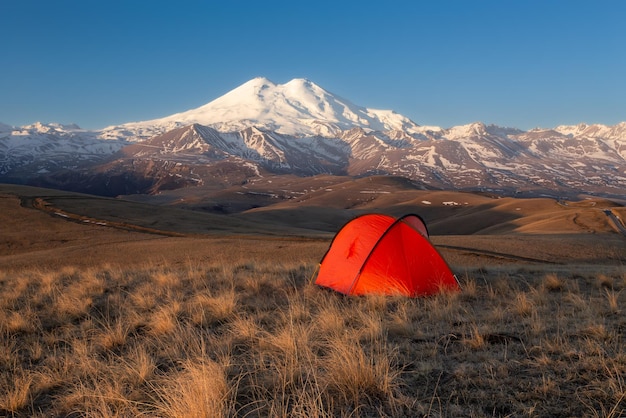 Amanecer de luz dorada con carpa roja brillante frente al monte Elbrus cubierto de nieve Cáucaso Rusia