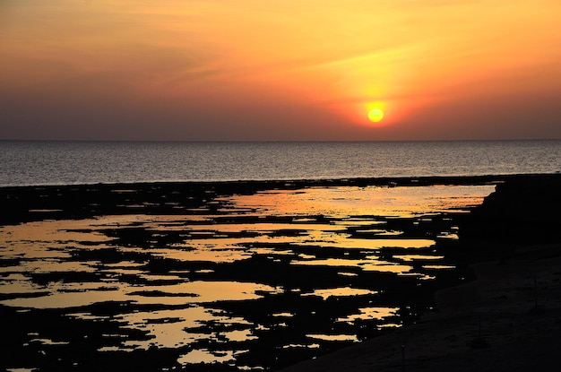 Amanecer en el mar con reflejos en la playa