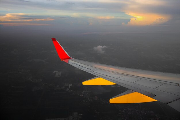 Amanecer matutino con ala de un avión volando sobre el océano La vista desde la ventana de un avión Foto aplicada a la imagen de los operadores de turismo para agregar un mensaje de texto o enmarcar el sitio web