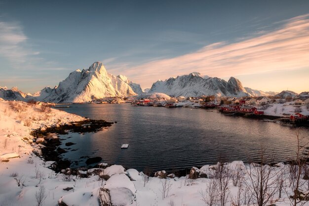 Foto amanecer en una montaña nevada con un pueblo escandinavo en la costa en invierno