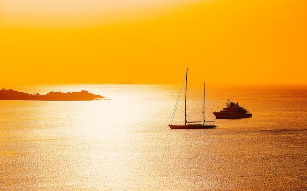 Amanecer o atardecer con yates en Porto Rotondo en Costa Smeralda en el mar Mediterráneo en Cerdeña, isla de Italia. Barco en Cerdeña en verano. Paisaje de la provincia de Olbia. Técnica mixta.