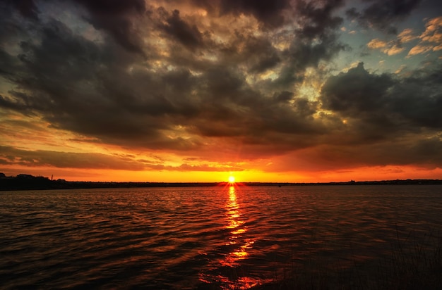 Amanecer a orillas de un río o lago con hermosas nubes