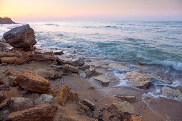 Amanecer paisaje la costa del mar rocoso y ondas de agua