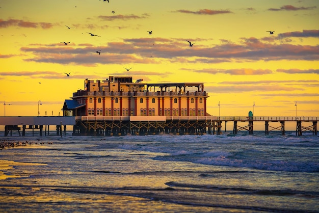 Amanecer sobre Daytona Beach Main Street Pier Florida con una bandada de gaviotas