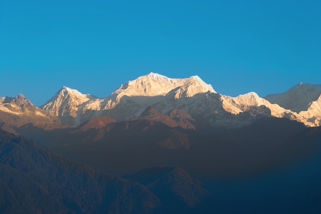 Amanecer sobre Kangchenjunga, India. Grandes montañas nevadas con cielo azul.