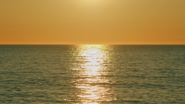 El amanecer sobre el mar tranquilo las olas del océano el movimiento relajante en la luz roja naranja del sol copia el espacio en cámara lenta