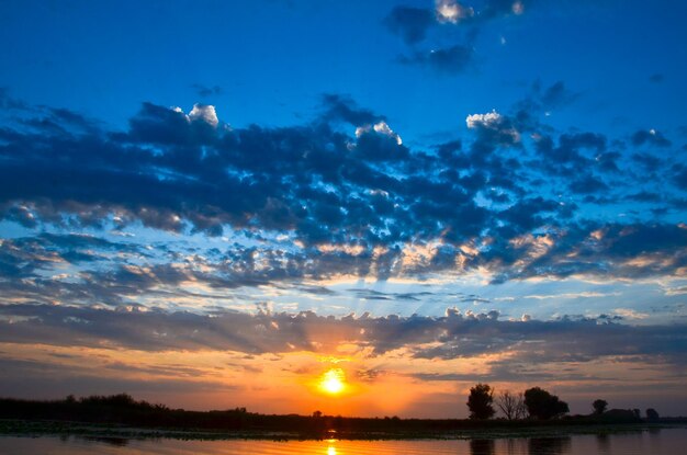El amanecer sobre el río en verano de las nubes con rayos