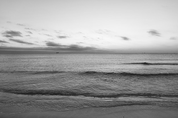 Amanecer temprano en la mañana sobre el mar Puesta de sol en el océano sobre el agua del mar con cielo al atardecer y siluetas de barco