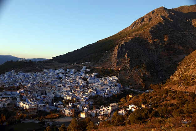 Amanhecer sobre a cidade de Chefchaouen Marrocos. Os raios do sol iluminam as encostas das montanhas e os telhados das casas. Cidade azul