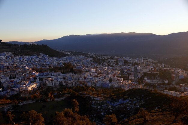 Amanhecer sobre a cidade de chefchaouen marrocos. os raios do sol iluminam as encostas das montanhas e os telhados das casas. cidade azul