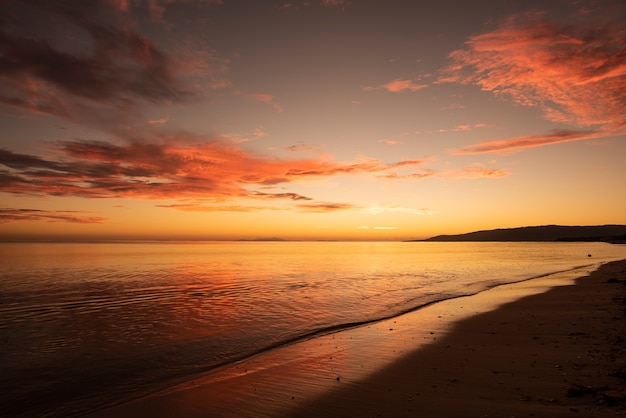 Amanhecer vibrante na costa refletindo suas cores vermelhas no mar. Ilha de Iriomote.