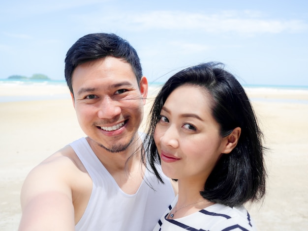 Amante asiático feliz dos pares em férias da praia do verão.