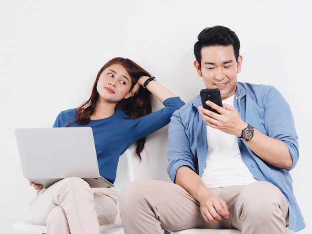 Amante asiático jovem casal lutando por um telefone inteligente na sala de estar em casa.