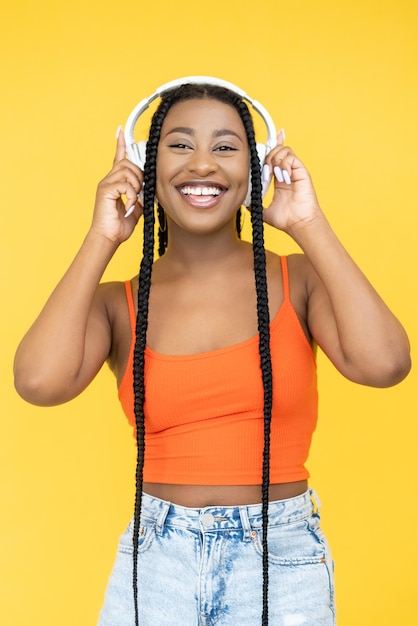 Amante da música Playlist divertido DJ acessório Alegre rindo mulher africana ouvindo música em fones de ouvido isolados em fundo laranja