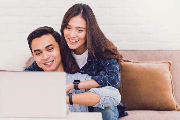 Amante de um jovem casal asiático trabalhando com um laptop em um quarto em casa