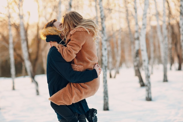 Amante de la joven pareja abrazándose besándose y divirtiéndose en el parque forestal de invierno.