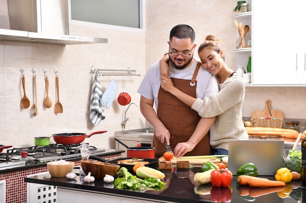 Amante joven pareja asiática cocinando en la cocina haciendo comida sana juntos sintiéndose divertido