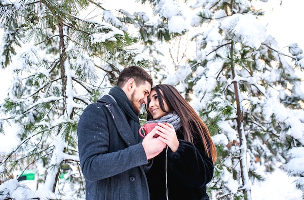 Amante joven pareja descansando en un bosque nevado. Abrazar y besar. concepto de vacaciones