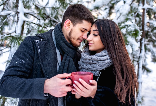 Amante joven pareja descansando en un bosque nevado. Abrazar y besar. concepto de vacaciones