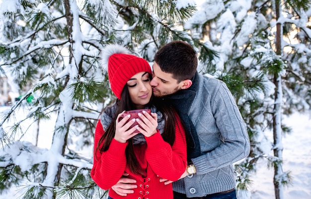 Amante joven pareja descansando en un bosque nevado. Abrazar y besar. concepto de vacaciones