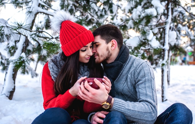 Amante joven pareja descansando en un bosque nevado. Abrazar y besar. concepto de vacaciones