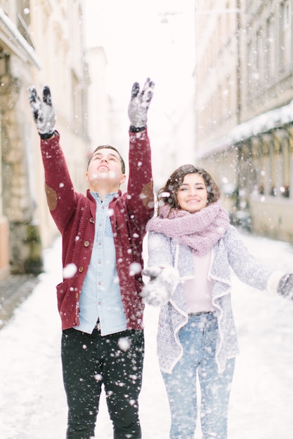 Amante joven pareja está jugando con nieve y camina en la mañana ciudad de invierno