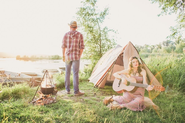 Amante joven pareja sexy cerca de la tienda del campamento Pareja de camping enamorada Parejas de amantes turistas relajarse en la naturaleza Viaje de campamento con amantes Pareja despreocupada cerca de fogata concepto de libertad de hoguera