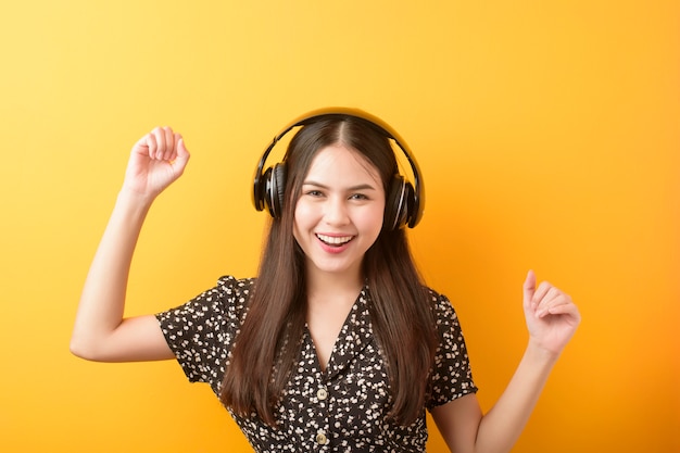Amante de la música mujer está disfrutando con auriculares sobre fondo amarillo