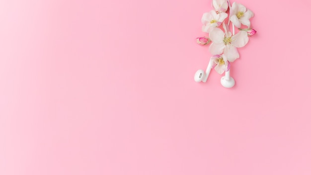 Amante de la música o concepto de música fresca plana sobre fondo rosa con flor de manzano y auriculares blancos. Foto de alta calidad