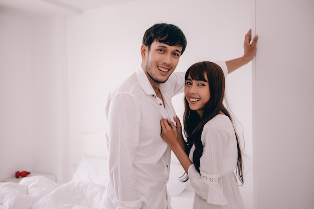 Amante de las parejas Acostado en la habitación de la cama Felicidad Estilo de vida y niña sonriente que se relaja en la cama blanca