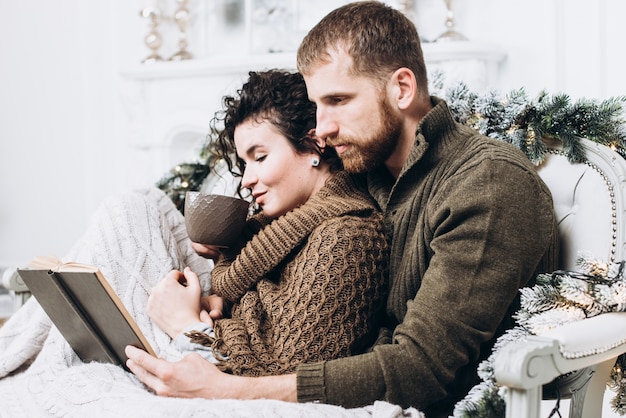 Amantes abrazándose y leyendo el libro en Navidad decorado interior