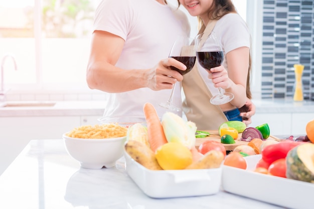 Amantes de Asia o parejas bebiendo vino en la cocina en casa