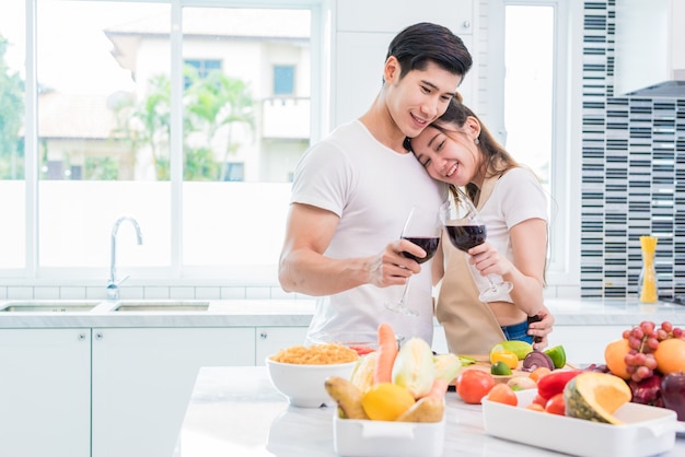 Amantes de Asia o parejas bebiendo vino en la cocina en casa