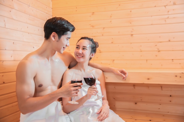 Amantes asiáticos bebiendo vino en la sauna