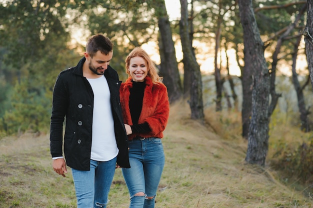 Amantes caminando de la mano en el parque otoño