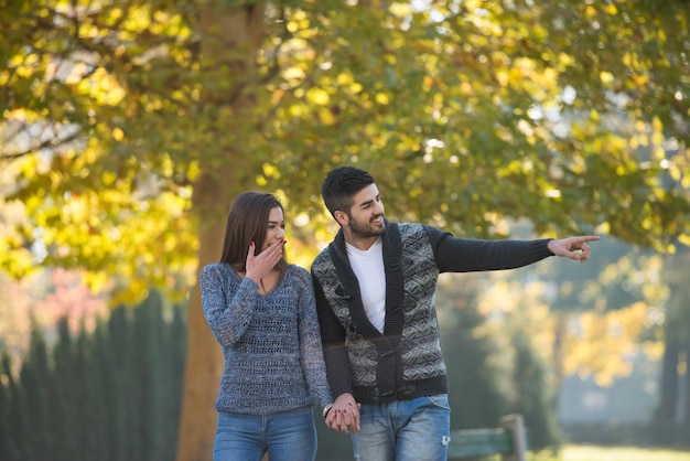 Amantes caminhando de mãos dadas no parque de outono