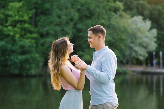 Amantes cara e garota segurando as mãos um do outro e sorrindo na natureza