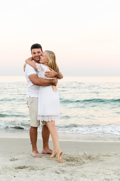 Foto los amantes cerca del océano se abrazan y se divierten. marido y mujer abrazos al atardecer cerca del mar.