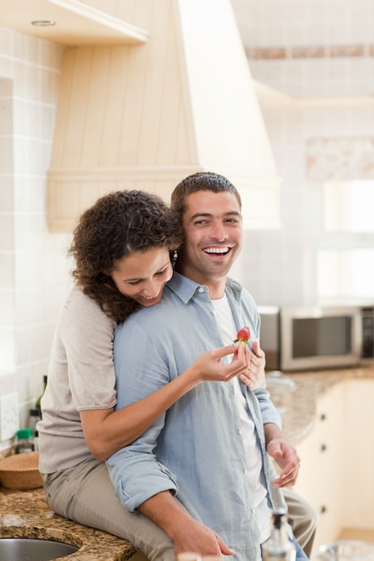 Amantes comendo um morango na cozinha