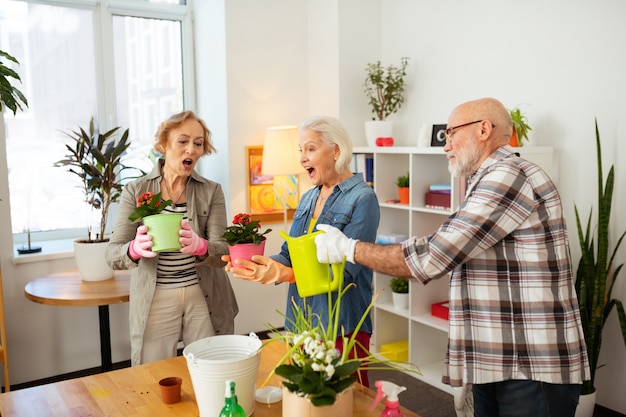 Amantes das flores. mulheres simpáticas e animadas sorrindo enquanto seguram seus vasos de flores