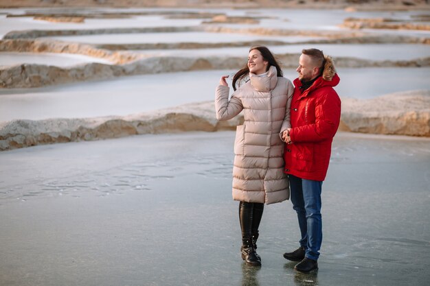 Amantes em jaquetas andam no gelo de poços de areia